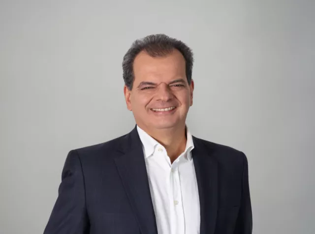 Head shot of middle aged man smiling at the camera in a white dress shirt and dark blue blazer