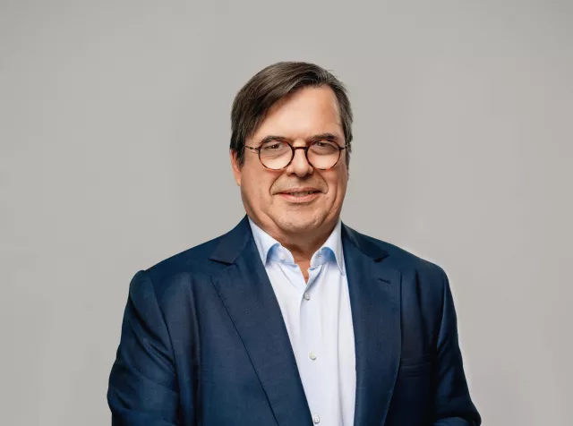 Headshot of François-Xavier Bellon, older man with brown hair in a dark blue blazer with glasses, looking at camera smiling