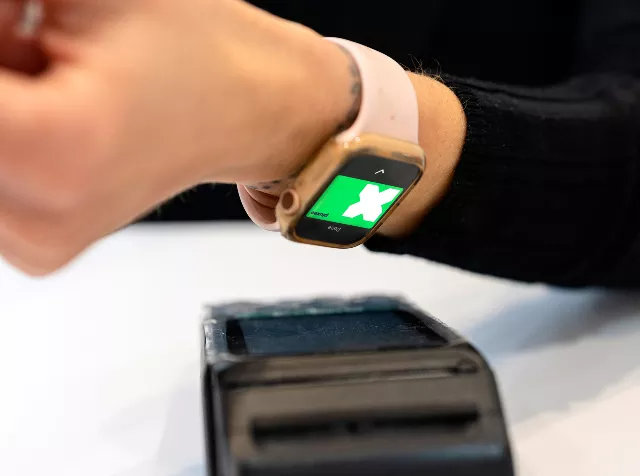 close up of arm tapping to pay with pluxee card on wrist watch 