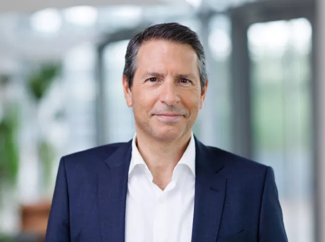 Headshot of Manuel Fernandez​, a man with dark hair, wearing a dark blue blazer and white dress shirt, smiling 