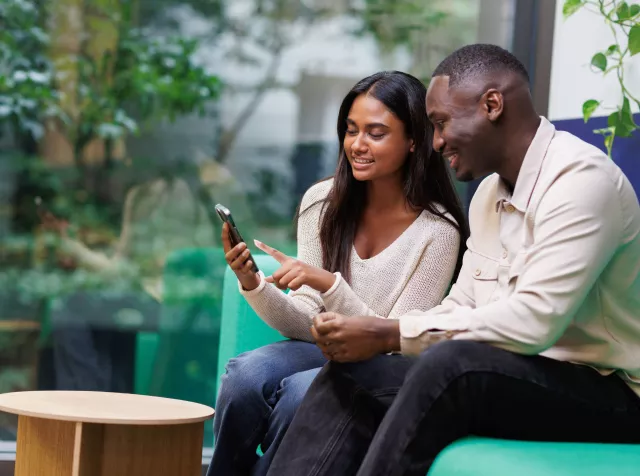 Man and woman on a couch, looking at a phone