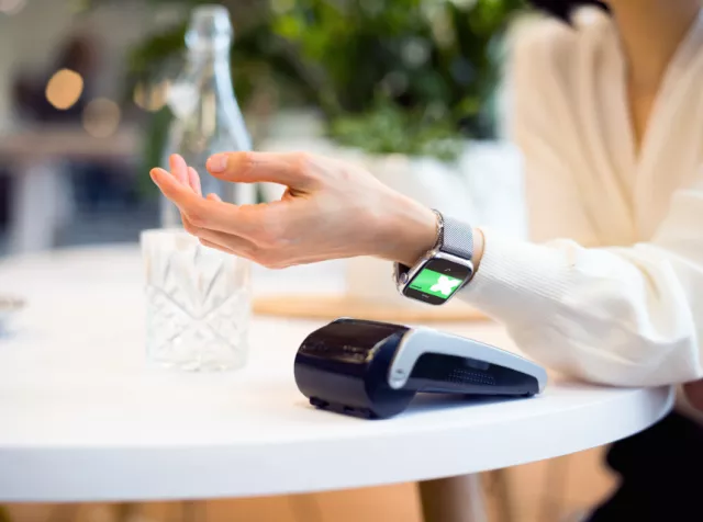 Woman paying with her Pluxee card through her Apple watch at a restaurant