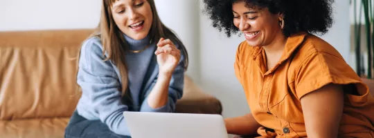 Two women looking at a laptop smiling
