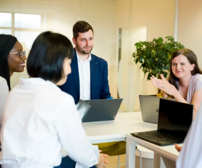diverse group talking around a table at work with laptops