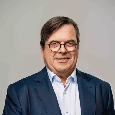 Headshot of François-Xavier Bellon, older man with brown hair in a dark blue blazer with glasses, looking at camera smiling