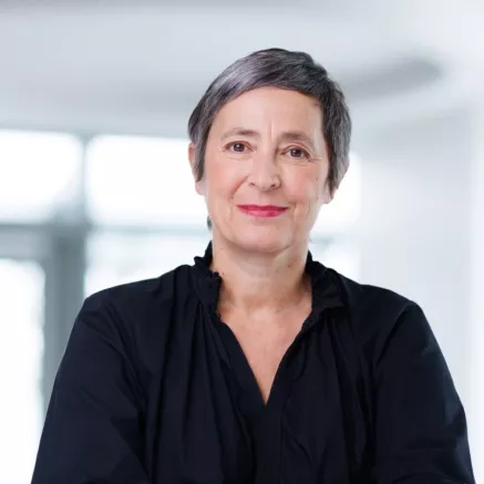 Headshot of Laure Pourageaud​, woman with short grey hair, wearing a black shirt 