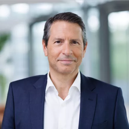Headshot of Manuel Fernandez​, a man with dark hair, wearing a dark blue blazer and white dress shirt, smiling 